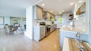 Een ruime keuken met moderne apparatuur, een eetgedeelte met rieten meubels en uitzicht op de omgeving.
