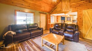 A cozy cabin interior with a wooden ceiling, a leather sofa, a wooden coffee table, and a kitchen area visible through an open door. - Private Lake & Dock: Log Cabin, 2 Mi to Clay! (Clay)