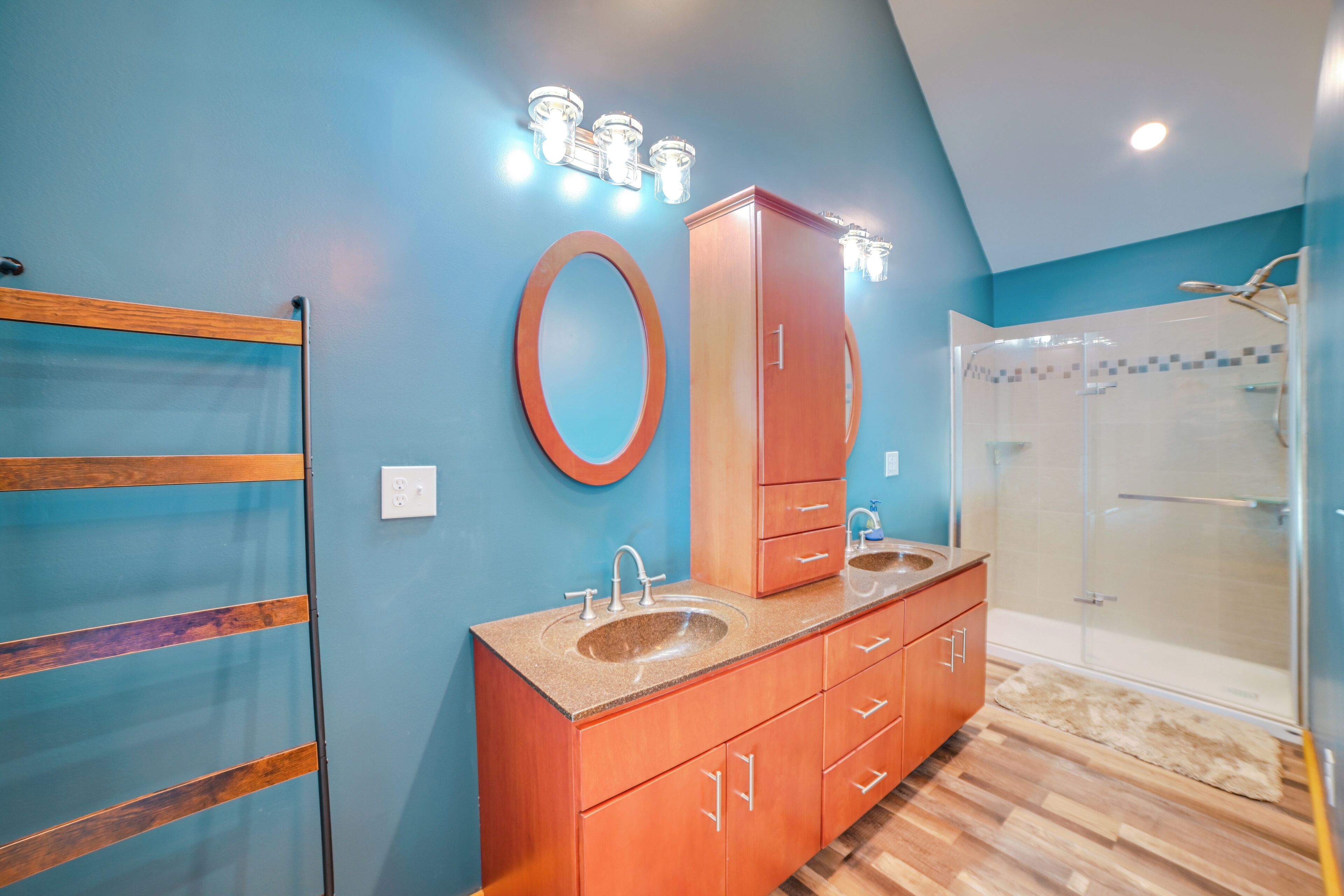 Un baño con tocador de madera, un espejo grande y cabina de ducha de vidrio.