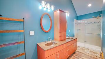 Un baño con tocador de madera, un espejo grande y cabina de ducha de vidrio.