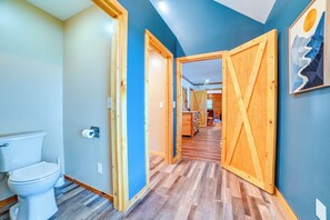 A hallway with wooden doors, a toilet, and a wooden floor. - Private Lake & Dock: Log Cabin, 2 Mi to Clay! (Clay)