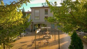 Een hotel binnenplaats met buitenmeubilair, een fontein en een trap naar de ingang.