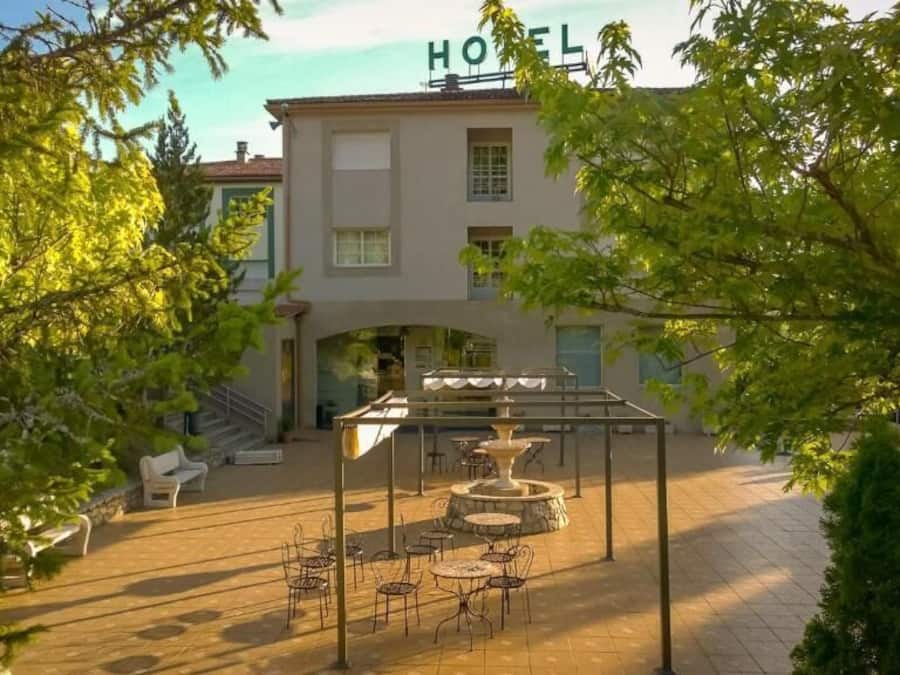 Ein Hotelinnenhof mit Außenbestuhlung, einem Brunnen und einer Treppe zum Eingang.