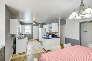 A compact kitchen with white cabinets, a central island, and a dining area with a red checkered tablecloth. - Quaint Family Retreat in Fairbury! (Fairbury)