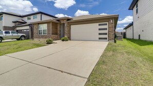 Une maison moderne à deux étages, dotée d’un garage, d’une allée et d’une pelouse bien entretenue.