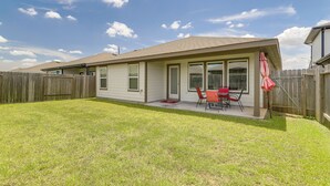 Une maison de plain-pied avec un patio couvert, une cour cl ôturée et un parasol rouge.