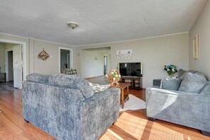 A living room with a grey sofa, a grey armchair, a wooden coffee table, and a TV.