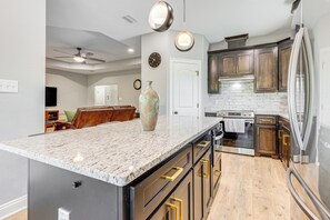 A modern kitchen with a marble countertop, stainless steel appliances, and wooden cabinets.