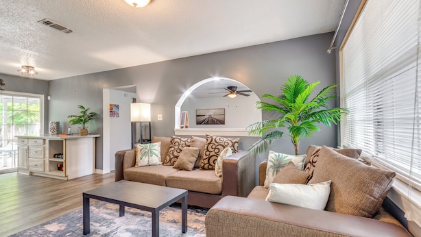 A modern living room with a sofa set, a coffee table, and a dining area with a white cabinet. - Game, Swim & Explore: Family Home in Pensacola (Pensacola)
