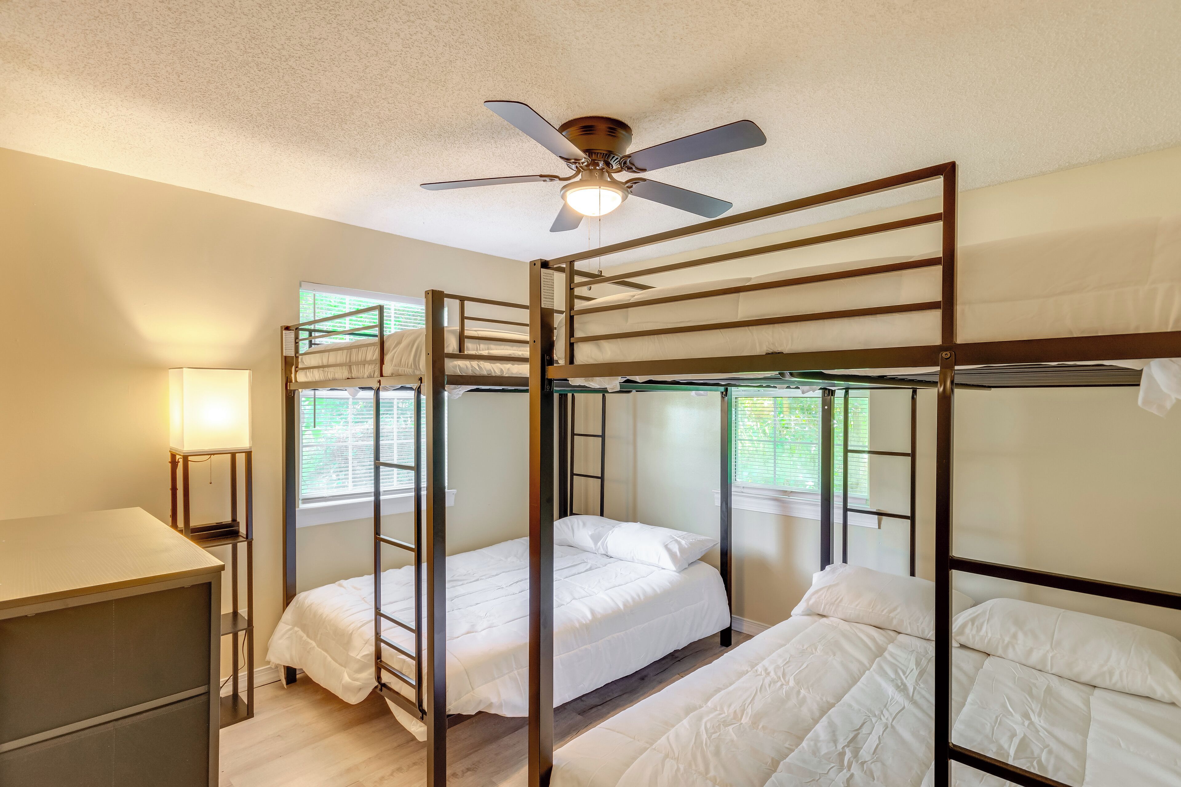 Dormitorio con literas, ventilador de techo, escritorio y ventana con persianas.