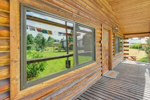 A log cabin with large windows, a wooden deck, and a picnic table.