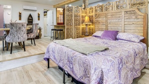 A bedroom with a large bed, a wooden headboard, a desk with a chair, and a mirror. - 7 Mi to Kitty Hawk Pier & Beach: Studio w/ Patio! (Harbinger)
