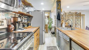 A modern kitchen with stainless steel appliances, wooden countertops, and a built-in oven. - 7 Mi to Kitty Hawk Pier & Beach: Studio w/ Patio! (Harbinger)