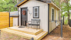 A small wooden cabin with a front door, a bench, and a small porch. - 7 Mi to Kitty Hawk Pier & Beach: Studio w/ Patio! (Harbinger)