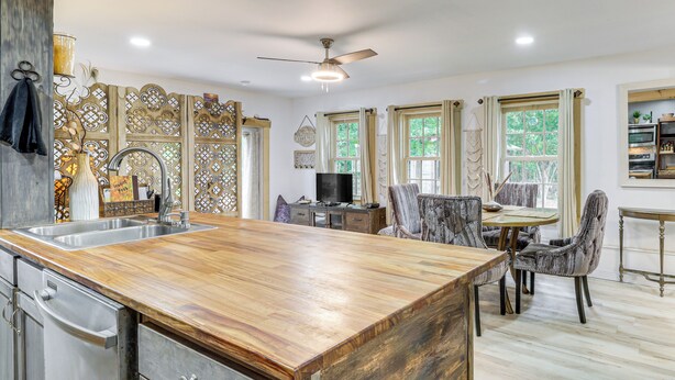A modern kitchen with a wooden countertop, stainless steel appliances, and a dining area with a table and chairs. - 7 Mi to Kitty Hawk Pier & Beach: Studio w/ Patio! (Harbinger)