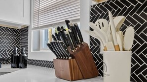 Eine Küche mit Messerblock, Besteckhalter und einer Spritzschutzwand.