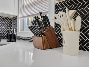 A kitchen counter with a knife block and a utensil holder.