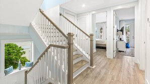 A staircase with white railings and wooden steps leading to a bedroom. - Heated Pool Elevator Game Room Ocean Decks (St. Augustine)