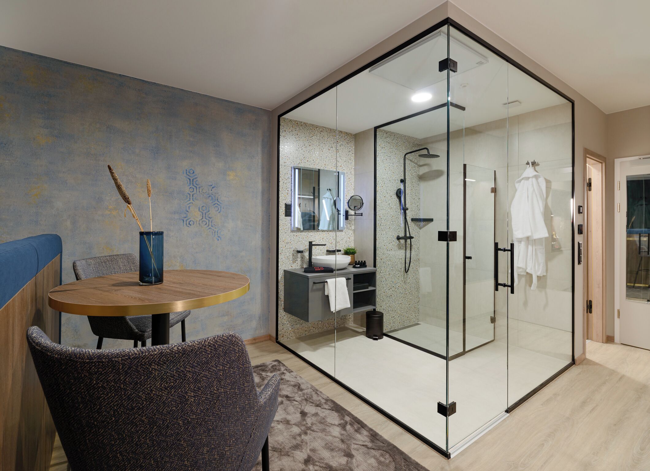 A modern bathroom with a glass shower enclosure, a sink, and a mirror.