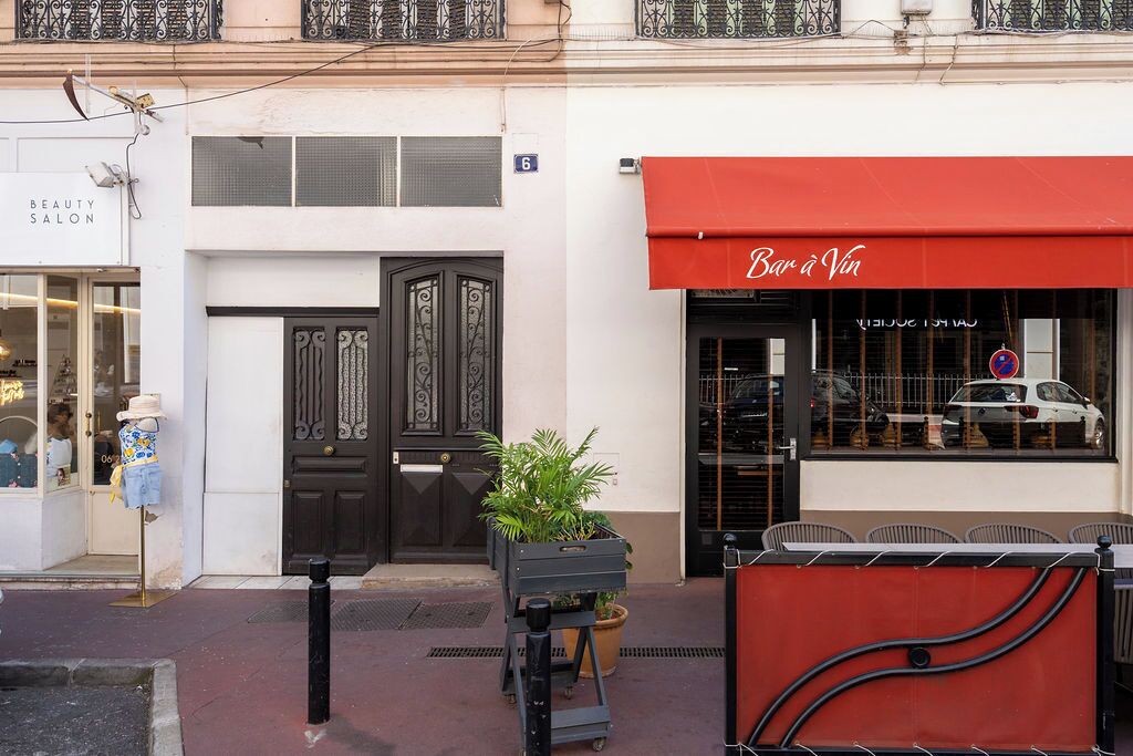 A building with a beauty salon on the left and a red awning with 'Bar à Vin' on the right.