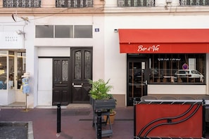 A building with a beauty salon on the left and a red awning with 'Bar à Vin' on the right.