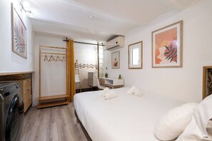 A hotel room with a bed, a desk, a chair, a wardrobe, and a washing machine.