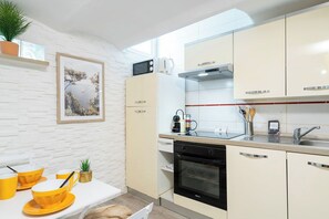 A modern kitchen with white cabinetry, a microwave, a stove, and a sink. - Le Mimosa mignon en plein centre-ville (Cannes)