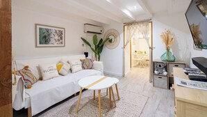Un salon moderne avec un canapé, une table basse ronde, un téléviseur et un bureau avec un ordinateur.