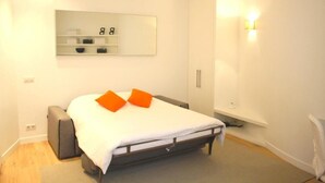 Quarto com cama, mesa de cabeceira, guarda-roupa e espelho na parede.