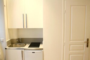 A compact kitchen with white cabinets, a stainless steel sink, and a built-in oven.