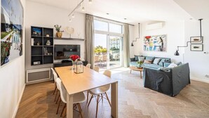 A modern living room with a sofa, a dining table, and a TV. - Le Boréal penthouse, terrasse et vue panoramique (Cannes)