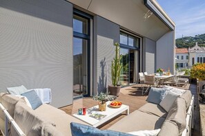Un espace de vie extérieur moderne comprenant un canapé, une table basse et un ensemble de mobilier de salle à manger.