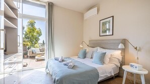 A hotel bedroom with a large bed, a bedside table, a window with a view of the outdoors, and a ceiling fan. - Le Boréal penthouse, terrasse et vue panoramique (Cannes)