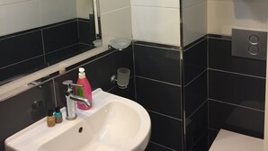 Un baño con lavamanos blanco, un espejo, un inodoro y un perchero para toallas.