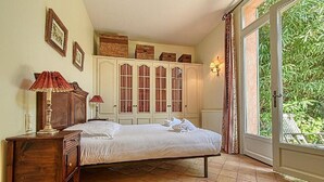 A bedroom with a bed, a nightstand, a dresser, and a window with curtains. - L'Oranger maison pittoresque (Cannes)