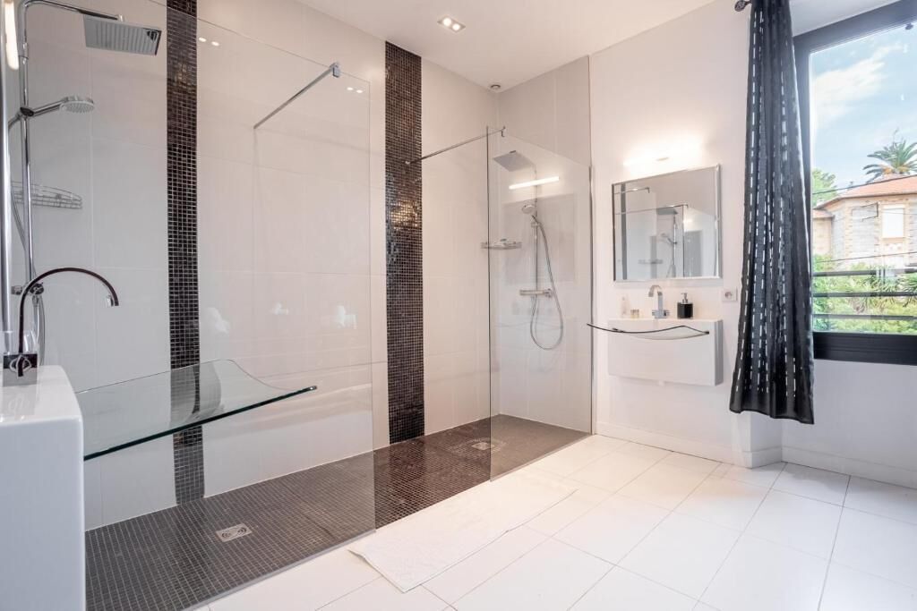 Une salle de bain moderne avec une douche à parois de verre, un meuble-lavabo en verre et un grand miroir.