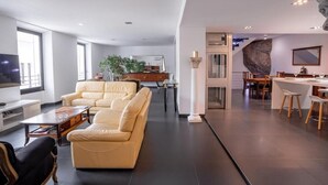 Ett modernt vardagsrum med en beige soffa, en matplats med en stor sten som dekorativt inslag och ett kök i bakgrunden.