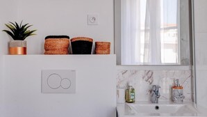 A bathroom with a white sink, a mirror, and a potted plant. - La Panthère studio design central et calme (Cannes)