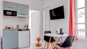 A compact kitchen with a microwave, a small refrigerator, and a dining area with a table and chairs. - La Panthère studio design central et calme (Cannes)