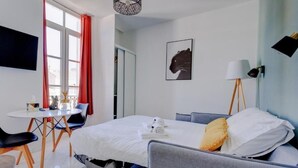 A modern hotel room with a bed, a desk, a chair, a lamp, and a picture on the wall. - La Panthère studio design central et calme (Cannes)