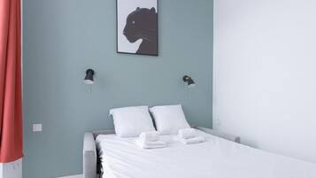 Una camera da letto con un letto, due cuscini, due lampade a parete e un quadro appeso.