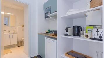 A compact kitchen with a dishwasher, a coffee maker, and a toaster on the counter.
