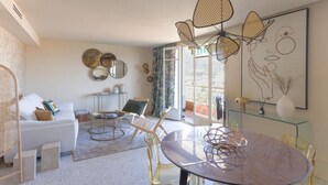 A modern living room with a round glass table, white sofa, and a large window.