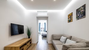 Una sala de estar moderna con un mueble bajo para el televisor de madera, un sofá gris y dos cuadros en la pared.
