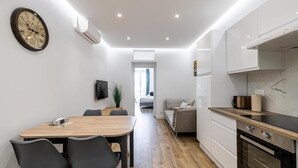 Una cocina moderna con armarios blancos, una mesa de comedor de madera y una estufa negra.