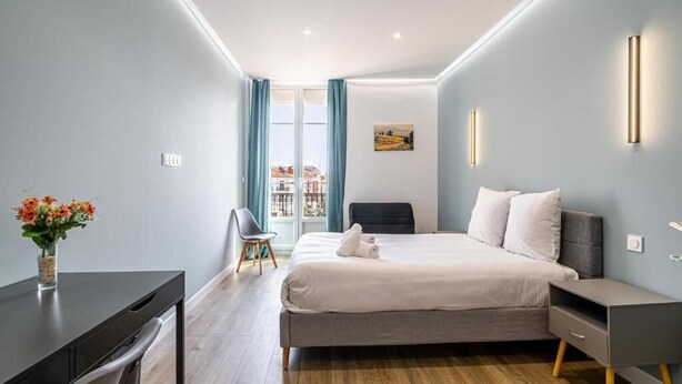 Una habitación de hotel moderna con cama, escritorio, silla y vistas a través del ventanal.