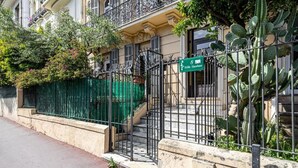 Un edificio residencial con una puerta verde, una escalera y un cactus al frente.
