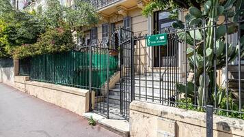 Un edificio residenziale con un cancello verde, una scala e un cactus sullo sfondo.