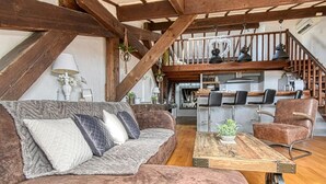 Un salon rustique avec un canapé en cuir marron, une table basse en bois et une cuisine en arrière-plan.