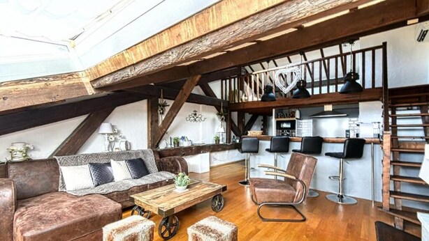 Un espace de vie de style loft avec un plafond en bois, un canapé, une table basse et des tabourets de bar.